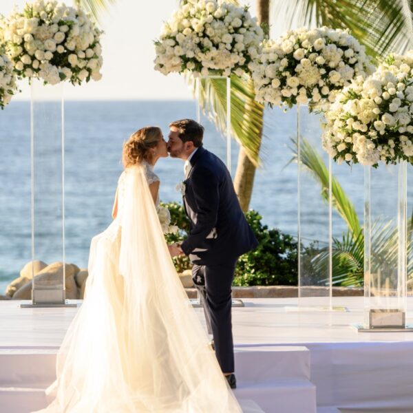 bride and groom in front the ocean with white flowers