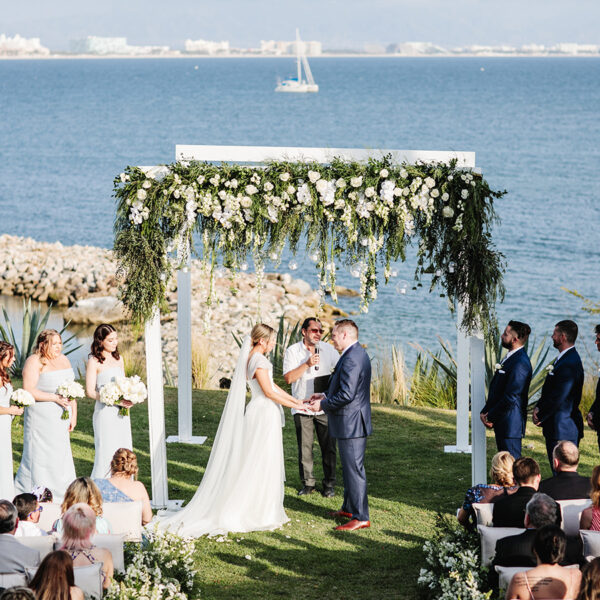 a bride and groom in front of priest in a cultural wedding with th ocean as background
